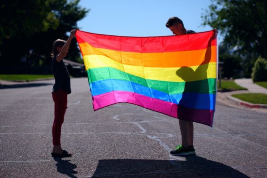 Two people holding an LGBT flag